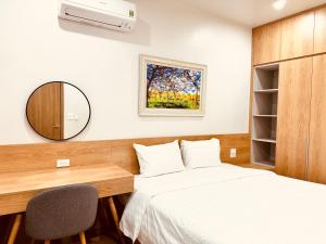 a bedroom with a bed and a desk and a mirror at Warm & Cozy Apartment in Hai Phong