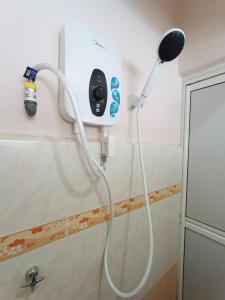 a shower with a white hose attached to a wall at Juwita Homestay Bukit Katil - Free Unifi and 15 Minutes To Town in Melaka