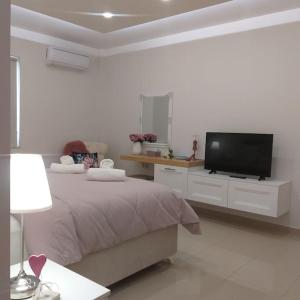 a white bedroom with a bed and a flat screen tv at Luxury apartment in the heart of the city in Chania Town