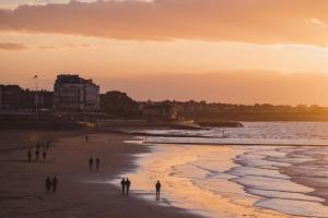 a group of people walking on the beach at sunset at No 42 by GuestHouse, Margate in Margate