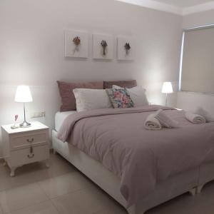 a white bedroom with a large bed and two lamps at Luxury apartment in the heart of the city in Chania Town