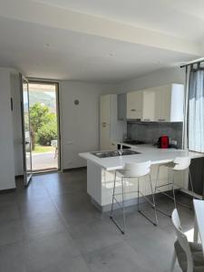 a white kitchen with a counter and chairs in it at casa verdemare in Cefalù