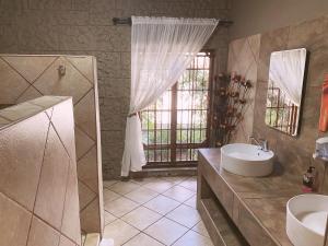 baño con lavabo, espejo y ventana en The Wilds Lodge, en Kuruman
