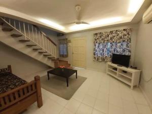 a living room with a staircase and a television at Juwita Homestay Bukit Katil - Free Unifi and 15 Minutes To Town in Melaka