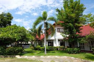 a white house with a palm tree in the yard at Karinthip Village in Chiang Mai