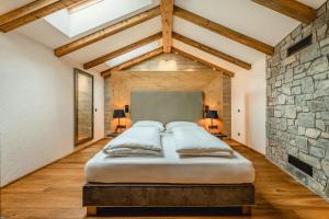 a large bed in a room with a stone wall at Apartmenthaus Wiesenhof in Aschau