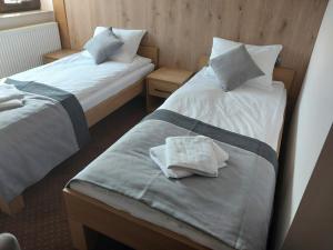 Dos camas en una habitación de hotel con toallas. en Makarewicz Dworek en Szypliszki