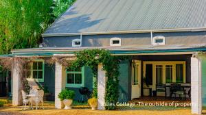 a blue house with a porch with chairs and tables at Julie's Cottage in Riebeek-Kasteel