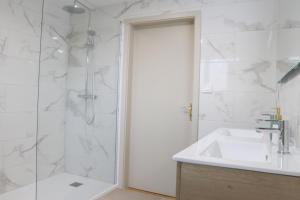 ein weißes Bad mit einer Dusche und einem Waschbecken in der Unterkunft Le Tropical, Chic & Design in Wahlbach