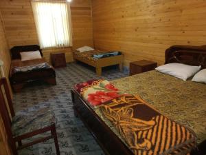 a room with two beds and a chair and a table at Тур центр Вилящ in Masallı