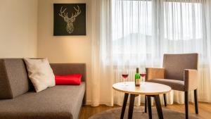 a living room with a couch and a table with a wine glass at Gasthaus Hirschenstube & Gästehaus Gehri in Waldkirch