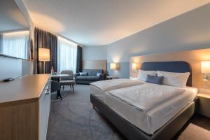 a hotel room with a bed and a desk at Vienna House Easy by Wyndham Frankfurt Airport in Kelsterbach