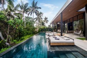 een overloopzwembad met banken en een huis bij Villa Homala by BaliSuperHost in Ubud