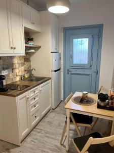 una cocina con armarios blancos, una mesa y una puerta en My Naxian Home 1 en Agios Prokopios