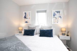 biała sypialnia z dużym łóżkiem z niebieskimi poduszkami w obiekcie Shakespeare's Nest w mieście Stratford-upon-Avon