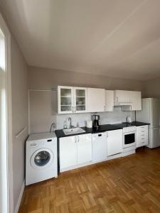 a kitchen with white cabinets and a washer and dryer at Apartment in historical house in Oslo