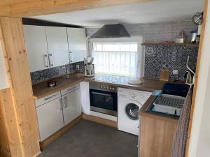 a kitchen with white cabinets and a washer and dryer at Bungalow im Grünen in Werneuchen +5 photos
