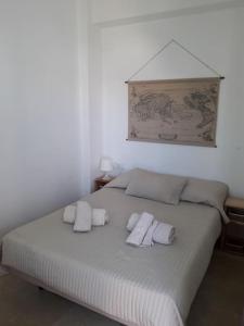 a white bed with three white towels on it at Ático en Rota, junto a la playa in Rota