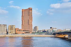 un grand bâtiment à côté d'une rivière avec un pont dans l'établissement Ramses Hilton Hotel & Casino, au Caire