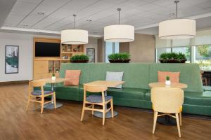 a green couch in a waiting room with tables and chairs at Home2 Suites by Hilton Austin Round Rock in Round Rock