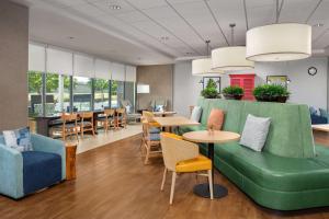 a waiting room with a green couch and tables and chairs at Home2 Suites by Hilton Austin Round Rock in Round Rock