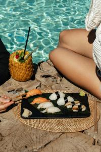 a woman sitting next to a pool with a plate of sushi at Divino Caldera in Akrotiri