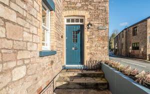 uma casa de tijolos com uma porta azul numa rua em Holmleigh cottage em Tintern