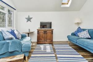 a living room with two blue couches and a tv at 28 Marsh Road in Gurnard