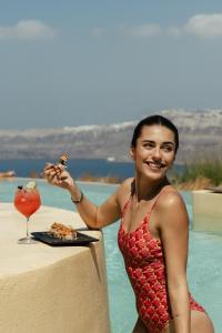 a woman standing next to a table with a drink at Divino Caldera in Akrotiri