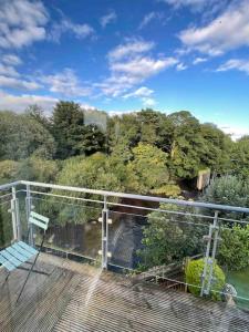una terraza con vistas al río y a los árboles en Modern Apartment by river - 20 mins to Belfast, en Dunadry