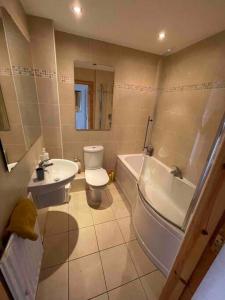 y baño con aseo, bañera y lavamanos. en Modern Apartment by river - 20 mins to Belfast, en Dunadry