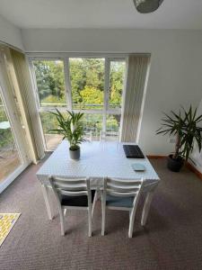 una mesa blanca con 2 sillas y un ordenador portátil. en Modern Apartment by river - 20 mins to Belfast, en Dunadry