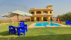 uma casa com um guarda-sol e cadeiras e uma piscina em فيلا للايجار في كمبوند سمر قند em El-Qaṭṭa