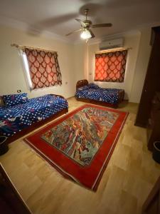 a room with two beds and a rug on the floor at فيلا للايجار في كمبوند سمر قند in El-Qaṭṭa