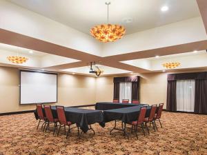 einen Konferenzraum mit einem Tisch, Stühlen und einem Bildschirm in der Unterkunft La Quinta by Wyndham Woodway - Waco South in Waco