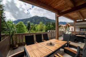 a wooden table and chairs on a deck with a mountain at Appartements Laura in Mayrhofen