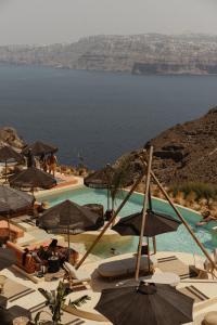 a view of a pool with umbrellas and the ocean at Divino Caldera in Akrotiri