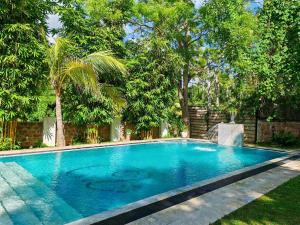 una gran piscina azul en un patio con árboles en Villa Lyvie ayurvedic hotel, en Tangalle