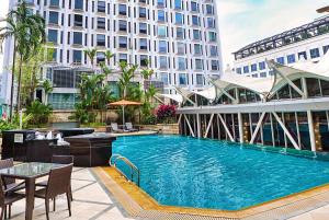 einem großen Pool mit einem Tisch und einem Gebäude in der Unterkunft Peninsula Excelsior Singapore, A Wyndham Hotel in Singapur