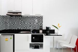 a kitchen with white cabinets and a black counter top at One World One Home Naiharn Hotel in Rawai Beach