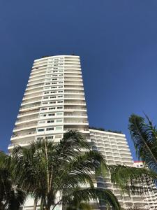 een hoog wit gebouw met palmbomen ervoor bij View Talay Condominium by Vlad Property in Pattaya South