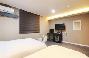 a hotel room with two beds and a flat screen tv at Hotel YOU in Yeosu
