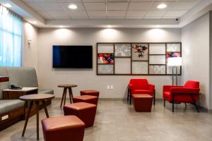 uma sala de espera com cadeiras vermelhas e uma televisão de ecrã plano em Hampton Inn Elkhorn Lake Geneva Area em Elkhorn