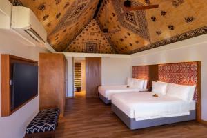 a bedroom with two beds and a flat screen tv at Outrigger Fiji Beach Resort in Korotogo