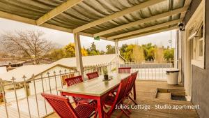 a patio with a wooden table and chairs on a deck at Julie's Cottage in Riebeek-Kasteel