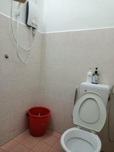 a bathroom with a toilet and a red bucket at Celine's Homestay in Taiping