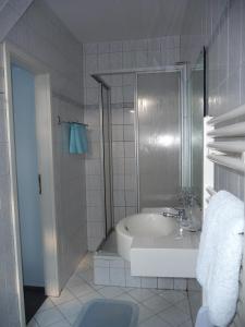 Baño blanco con bañera y lavamanos en Werners Landgasthaus en Lieskau
