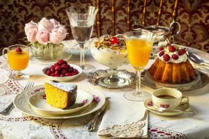 una mesa con un plato de pastel y vasos de zumo de naranja en Palazzo Arone dei Baroni di Valentino, en Palermo