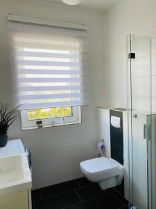 La salle de bains blanche est pourvue de toilettes et d'une fenêtre. dans l'établissement Ferienwohnung Sea-Bike-Soul, à Neubrandenbourg