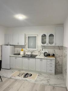 a kitchen with white cabinets and a white refrigerator at Knežević apartman in Podgorica